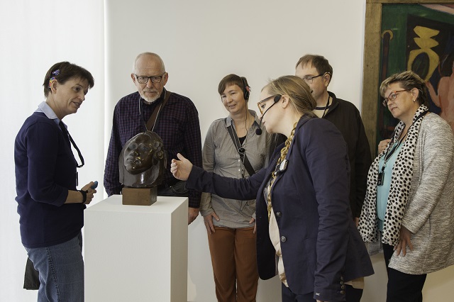 Eine Gruppe mit Cochlea Implantat Träger*innen betrachten eine Skulptur im Saarlandmuseum - Moderne Galerie